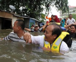 Ketua Fraksi Partai Keadilan Sejahtera (PKS), Hidayat Nur Wahid menerobos banjir untuk memberikan bantuan kepada warga korban banjir di Posko PKS Petamburan, Jakarta, (18/01). (ANTARA)