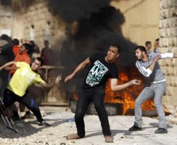Warga Palestina melempar baru dekat ban yang terbakar ketika bentrok dengan pasukan Israel di dekat Jenin. (yahoo.com)