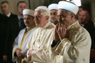 Paus Benediktus XVI berdoa sambil berdiri di samping Mustafa Cagrici, Mufti Agung Istanbul, menghadap kiblat dan menundukkan kepalanya. (AFP/BBC)