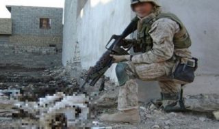 Foto seorang tentara Amerika Serikat sedang mengacungkan senjata ke jenazah pejuang Irak.  (foto: republika)