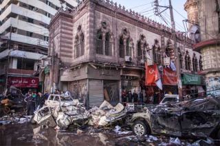 Warga Mesir menyaksikan puing-puing akibat ledakan bom mobil di depan kantor polisi di Kota Mansura, utara Kairo, Selasa (24/12/2013). Foto: MAHMOUD KHALED/afp