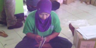 Siti Rohemah, melipat surat suara untuk mencari tambahan penghasilan di luar tugasnya sebagai guru honorer di Pamekasan. - Foto: kompas.com