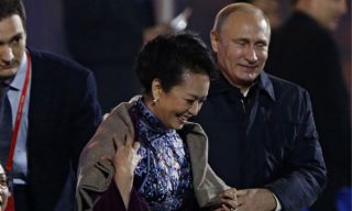 Putin saat memakaikan mantelnya ke Ibu Negara Tiongkok (theguardian.com)