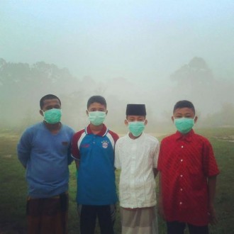 Warga dengan masker di antara kabut asap. (Ahmad Syaefullah)