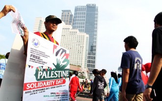 Relawan KNRP menggunakan Walkingboard event Palestine Solidarity Day sekaligus menyosialisasikan dengan selebaran yang diambil oleh warga yang melintas di arena Car Free Day, Bundaran HI, Jakarta Pusat, Ahad (22/11/15).  (KNRPMedia)