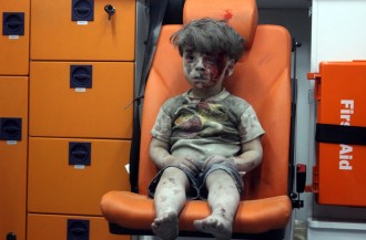 Bocah Suriah berusia 5 tahun, Omran Daqneesh, yang diselimuti debu dan darah, duduk di dalam ambulance setelah diselamatkan dari puing-puing reruntuhan bangunan yang terkena serangan udara Rusia di Aleppo pada 17 Agustus 2016. (Mahmoud Rslan / Getty Images)